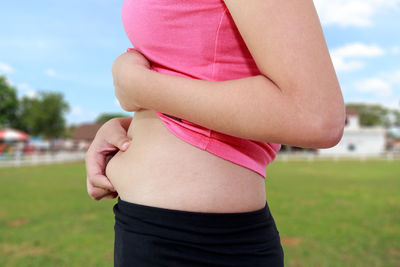 Midsection of woman holding belly while standing outdoors