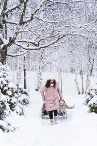 Woman standing on snow covered tree in winter