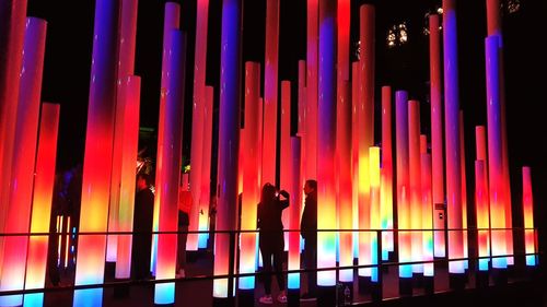 Rear view of silhouette man standing against illuminated building