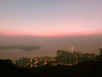 Illuminated buildings against sky during sunset