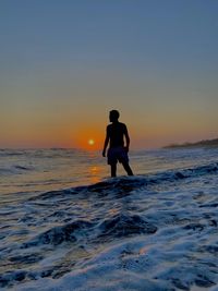 Full length of man standing on beach against sky during sunset