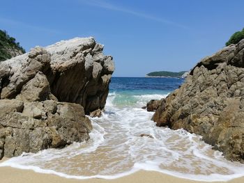 Scenic view of rocks on beach against sky