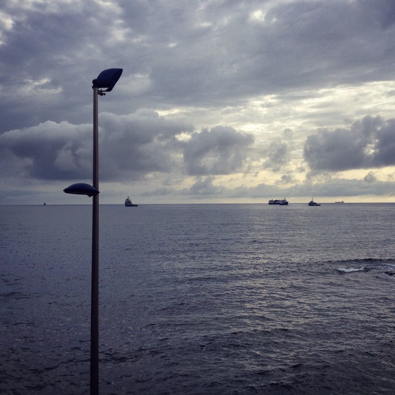 sea, water, horizon over water, sky, scenics, tranquility, tranquil scene, beauty in nature, cloud - sky, nautical vessel, nature, street light, cloud, waterfront, boat, transportation, cloudy, idyllic, silhouette, rippled