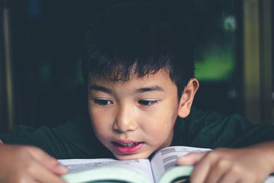 Close-up of boy reading book at home