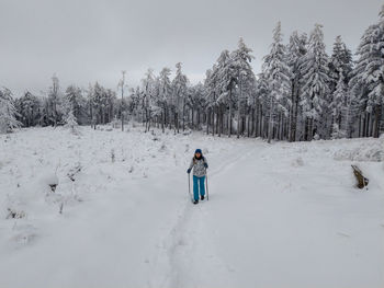 Rear view of people on snow covered field against sky