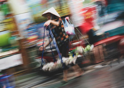 Blurred motion of woman walking on road in city