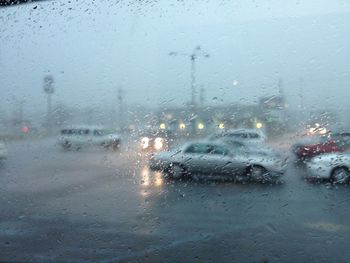 Cars on road seen through wet glass window