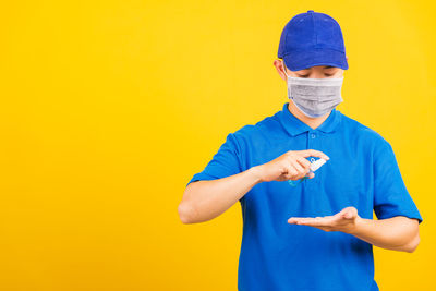 Full length of man standing against yellow background