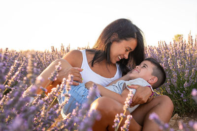 Young  woman plays with her son in a field of lavender flowers. enjoying family life in nature