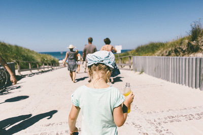 Rear view of friends on beach against sky