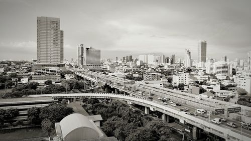 High angle view of bridge and buildings against cloudy sky