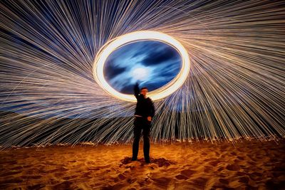 Full length of man spinning wire wools while standing at beach against sky