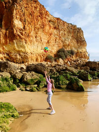 Full length of woman standing on rock against water