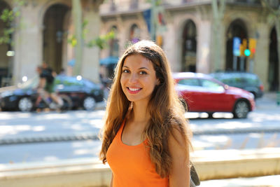 Portrait of smiling young woman standing on city street