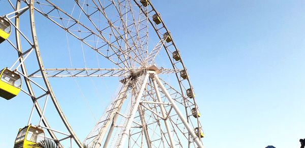 Low angle view of ferris wheel against clear blue sky