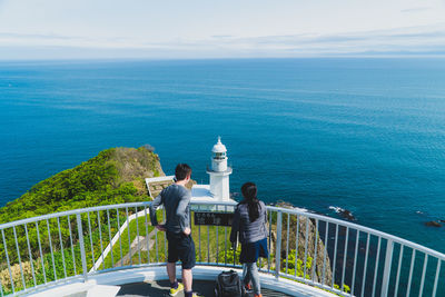 Rear view of people looking at sea against sky