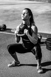 Athlete lifting weight while crouching outdoors