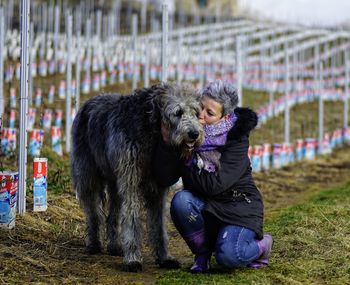 Woman kissing dog on field