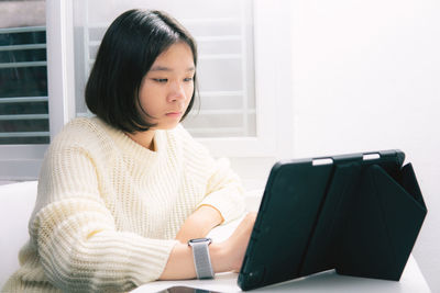 Woman looking away while sitting on table