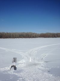 Scenic view of snow covered land against clear blue sky