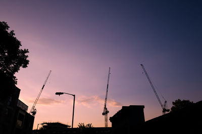 Low angle view of silhouette cranes against sky during sunset