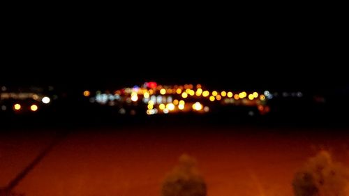 Defocused image of illuminated city against sky at night