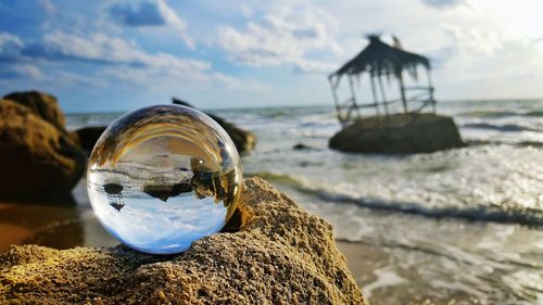 Close-up of crystal ball on beach against sky