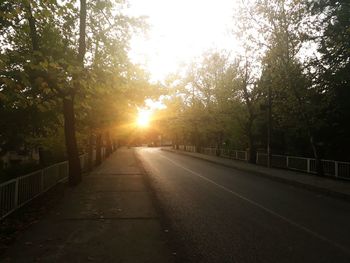 Road amidst trees against sky during sunset