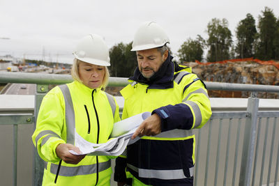 Engineers in reflecting clothing looking at blueprints