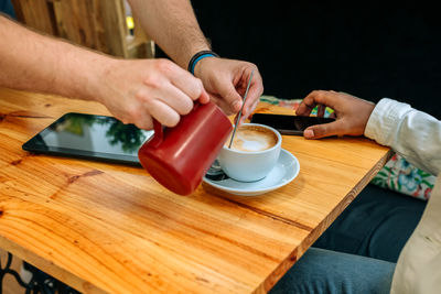 Midsection of man holding coffee on table