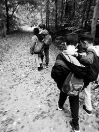 Rear view of people walking on bare trees