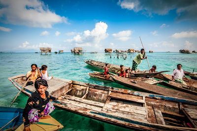 Rear view of people on boat in sea against sky
