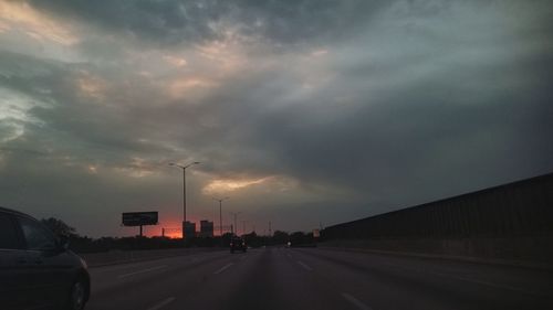 Cars on road against sky at sunset