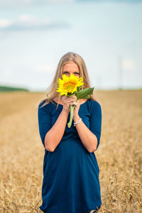 Woman holding yellow flower in field