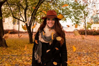 Young woman wearing hat standing against trees