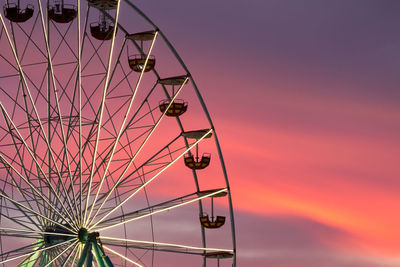 Low angle view of ferris wheel against sky at sunset