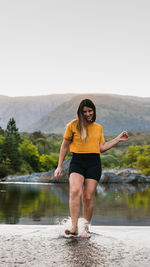 Full length of woman standing by lake against sky