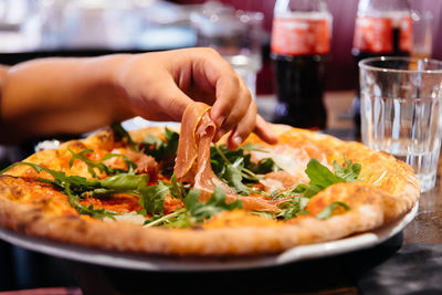 Cropped hand of woman having pizza on table