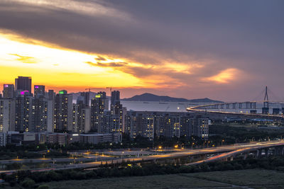 Illuminated buildings against sky during sunset in city