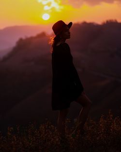 Side view of silhouette woman standing on beach during sunset