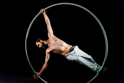 Low angle view of shirtless man against black background