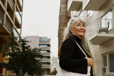 Senior woman standing in front of building