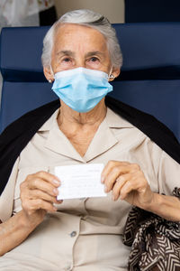 Portrait of senior woman wearing mask holding paper