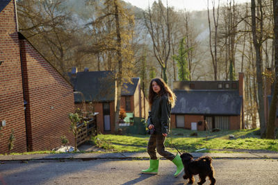 Full length of girl walking with dog on road