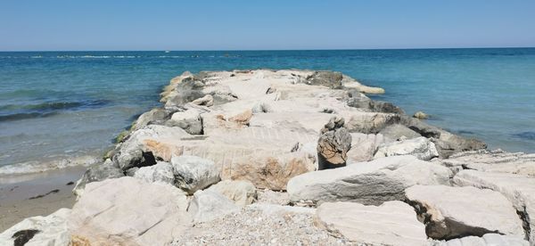 Rocks on beach against clear sky