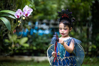 Cute little girl with expression face in halloween costume standing at at park.