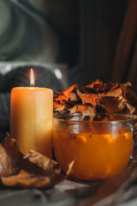 Burning candle and a large mug of hot orange sea buckthorn tea in a cozy home autumn 