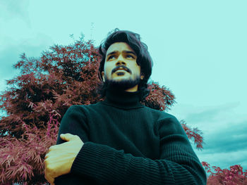 Portrait of young man looking away against sky
