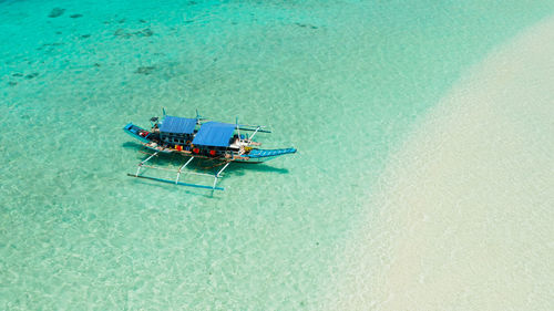 Boat on a tropical beach in the turquoise water of the lagoon from above. mansalangan sandbar. 