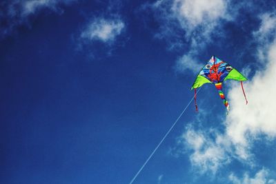 Low angle view of multi colored kite flying in blue sky